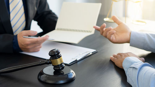 Midsection of man using mobile phone while sitting on table