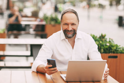 Man using mobile phone while sitting on table