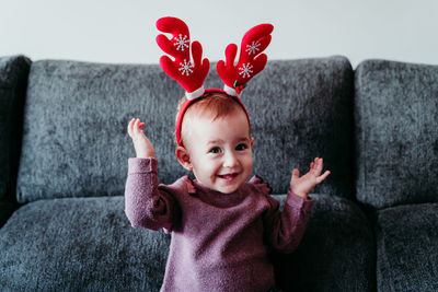 Cute smiling baby girl sitting on sofa at home