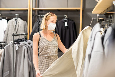 Mid adult woman wearing flu mask shopping at clothing store