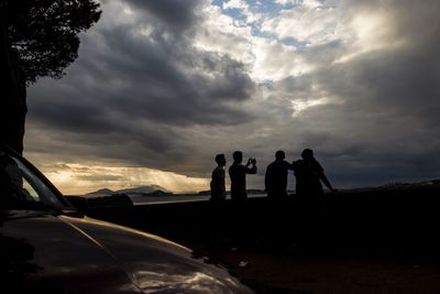 People on road against dramatic sky