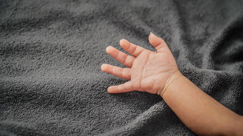 Close-up of baby hand on bed