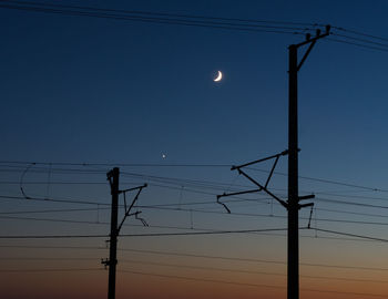 Low angle view of silhouette electricity pylon against clear sky during sunset