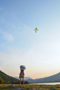 Low angle view of boy flying kite against sky