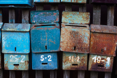 Close-up of mailboxes hanging on wooden fence