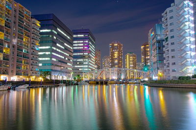 Illuminated buildings by city against sky at night