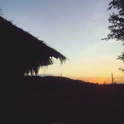 Silhouette trees on landscape against sky at sunset