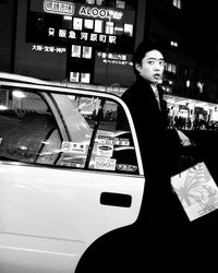 Portrait of woman standing by car at night