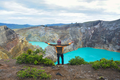 Rear view of man standing on mountain against sky