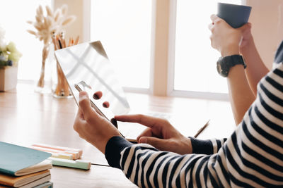 Midsection of woman using smart phone on table