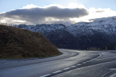 Road by mountains against sky during winter
