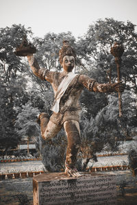 Woman statue against trees and plants