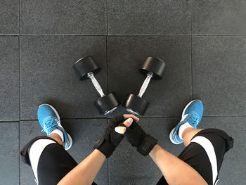 Low section of person with dumbbells on floor in gym