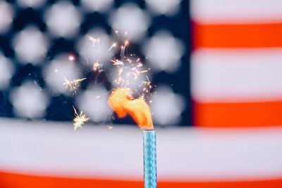 Close-up of illuminated firework against american flag