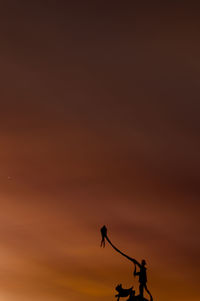 Silhouette power lines against sky during sunset