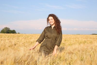 Happy woman standing on field against sky