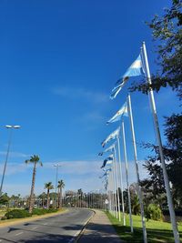 Road by trees against blue sky