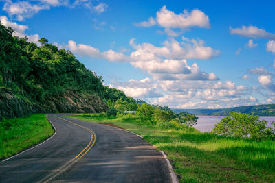 Road by trees against sky