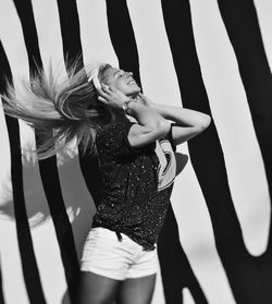 Young woman standing against patterned wall