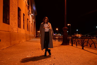 Full length of woman standing on street at night