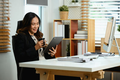 Young businesswoman using laptop while sitting on table