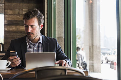 Businessman using tablet and cell phone in a cafe