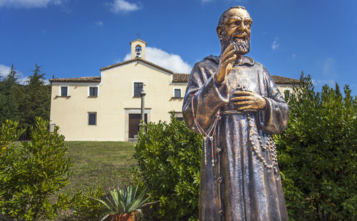 Statue against trees and building against sky