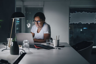 Confident businesswoman using laptop while working late night in office