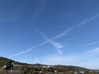 Low angle view of vapor trails against blue sky