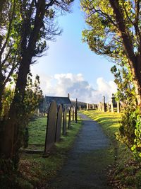 Wooden posts on footpath amidst field against sky