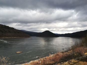 Scenic view of lake by mountains against sky