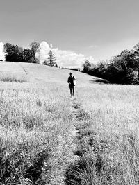 Man walking on field against sky