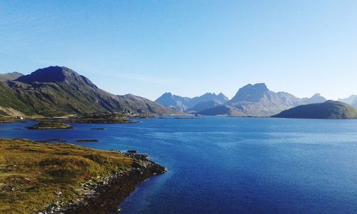 Scenic view of sea and mountains against clear blue sky