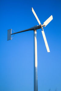 Low angle view of windmill against clear blue sky