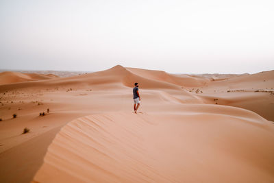 Man standing at desert against clear sky