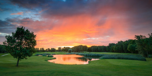 A stunning sunset over a golf course with a pond