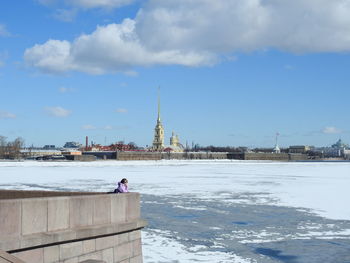 Buildings by lake against sky during winter