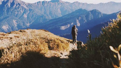 Man standing on rock against sky