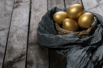 Golden easter eggs in birds nest over rustic wooden background with copy space