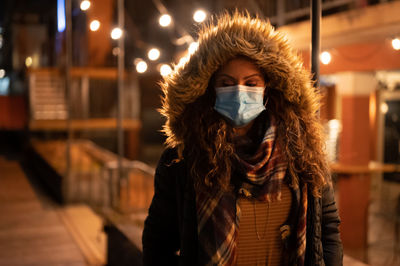 Portrait of woman wearing a mask at night in the city in 2020