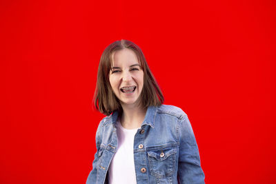 Portrait of a smiling young woman against red background