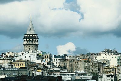 Buildings in karaköy city and galata tower  against cloudy sky