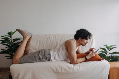 Young woman sitting on bed at home