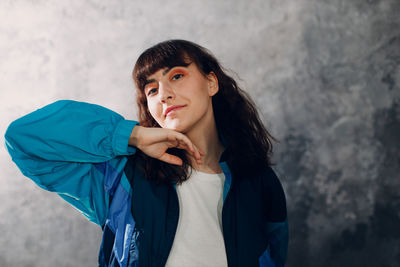 Portrait of young woman standing against wall