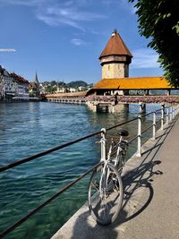 Bicycles on bridge over river against buildings in city