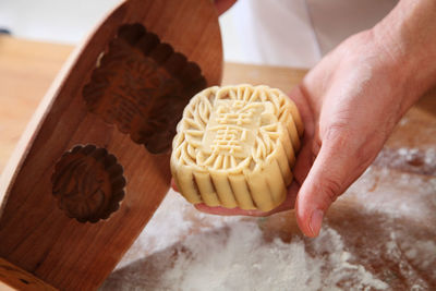 Close-up of hand holding cake slice on cutting board