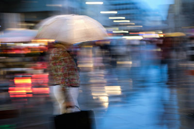 Blurred motion of people walking on wet street in rainy season