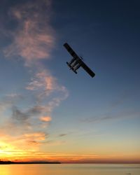 Low angle view of airplane flying against sky during sunset