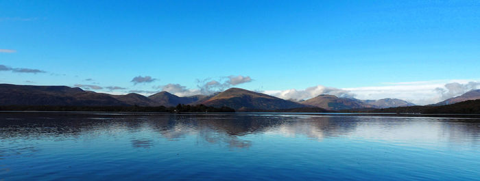 Scenic view of lake and mountains against blue sky