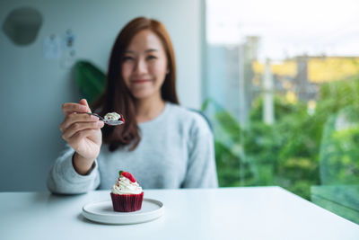 A beautiful asian woman holding and eating red velvet cup cake